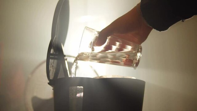 Glass of pouring water into the coffee maker