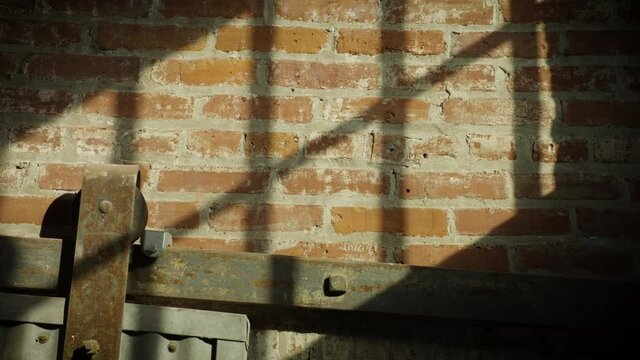 Hard sunlight shining on brick through the window of an old industrial-revolution era factory building.