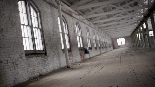 Twirling shot across the long hall of an old abandoned 1900s industrial factory in the city