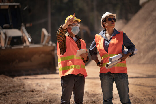 Two Surveyor builder Engineer technician  Business Team discuss plan at new construction site. High ground heavy industry and safety concept.