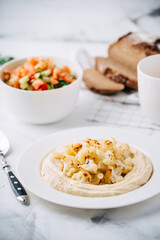 Hummus with cauliflower, tomato and cucumber salad, bread and coffee. Middle Eastern dish