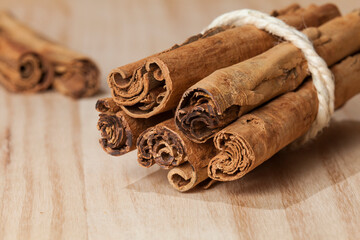 Several rolls of Canela en Rama tied with a rope; photo on wooden background.