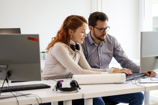 Two office workers discuss about a new project at the office. They looking a the computer screen.	
