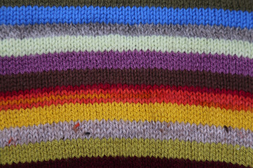 A close up view of part of a garment hand knitted in colourful stripes.