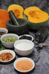 colorful spices and legumes, fresh parsley and stone mortar, pepper, hot pepper, coarse rock salt, black beans and yellow lentils and colored pepper, orange pumpkin sliced