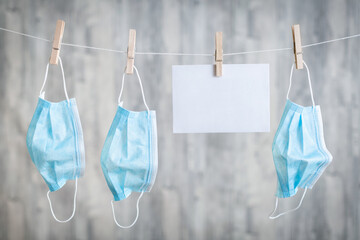 OP-Masken auf einer W&auml;scheleine mit einem wei&szlig;en Platzhalter f&uuml;r Text, Worte, Spruch in Zeiten von Corona, Covid 