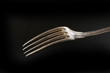 atmospheric photo of a turned dinner fork with blur in black background