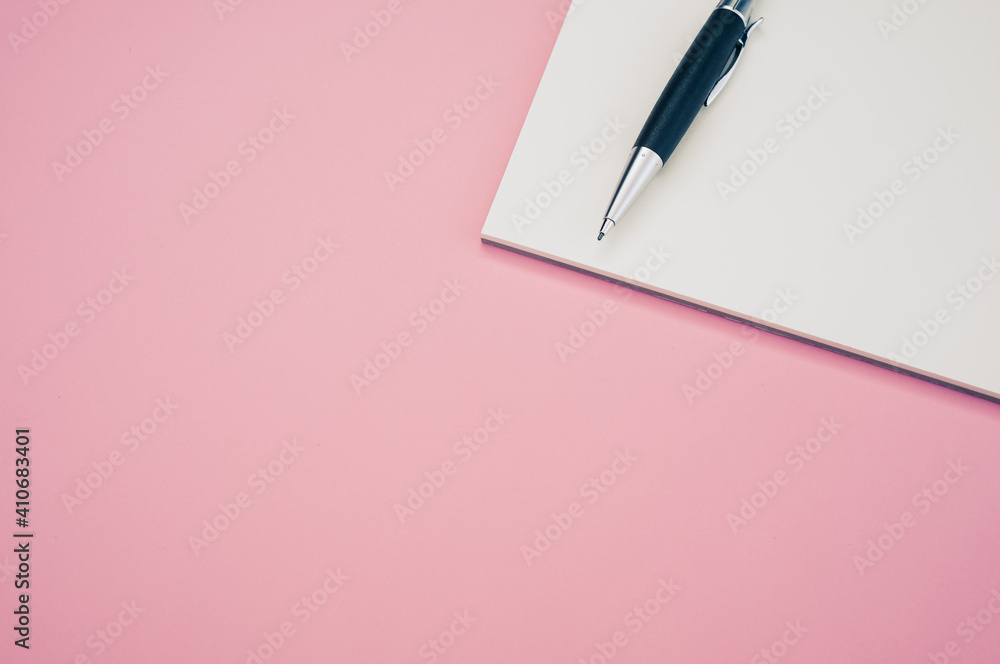 Poster top view closeup of a pen placed on an open notebook isolated on a pink background