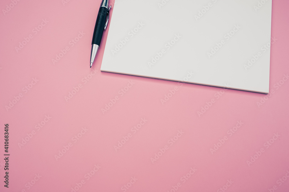 Poster top view closeup of a pen placed on an open notebook isolated on a pink background