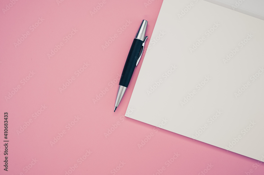 Poster top view closeup of a pen placed on an open notebook isolated on a pink background