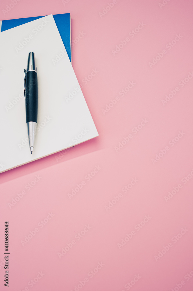 Poster top view closeup of a pen placed on an open notebook isolated on a pink background
