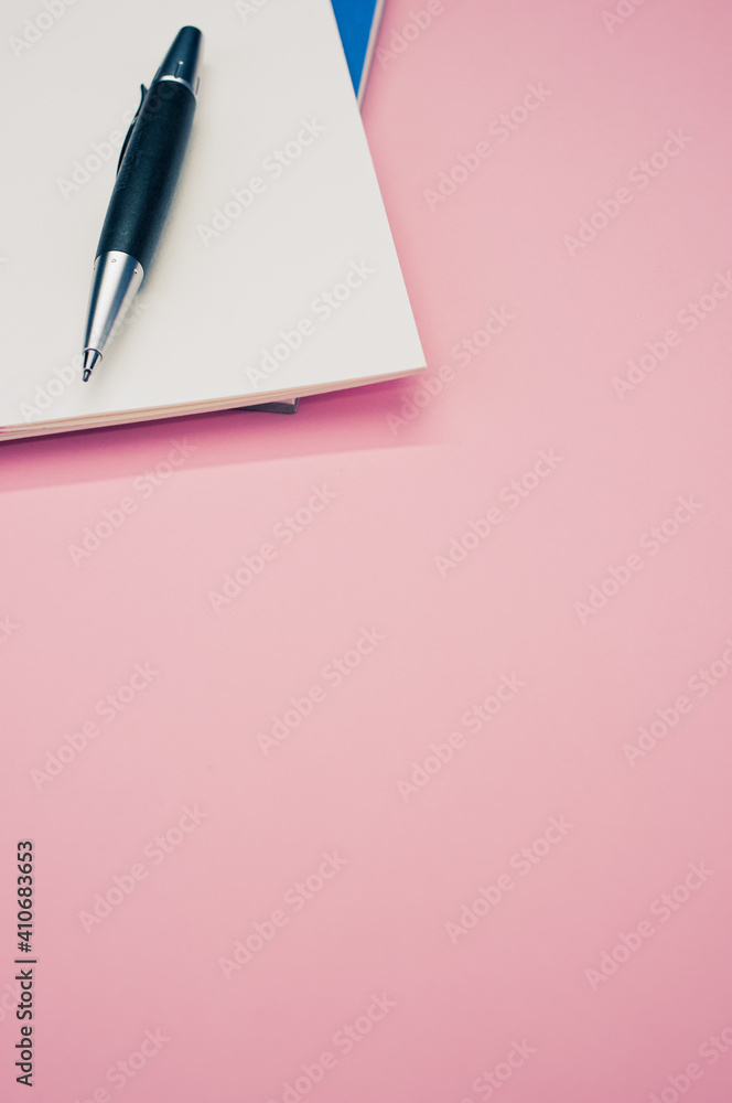 Poster top view closeup of a pen placed on an open notebook isolated on a pink background