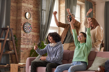 Family of four having fun together during playing video games at home © AnnaStills
