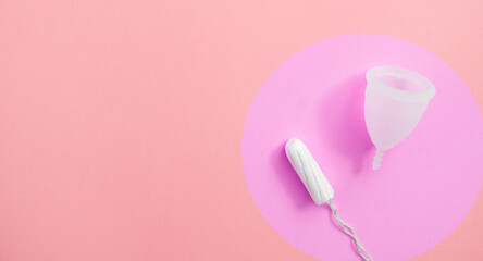 Tampon and menstrual cup in lilac circle on pink background with copy space