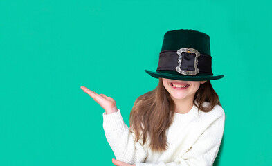 Portrait of cheerful smiling caucasian girl in fancy green leprechaun hat with gold buckle. concept promotion mockup. St. Patrick's Day. Copy space