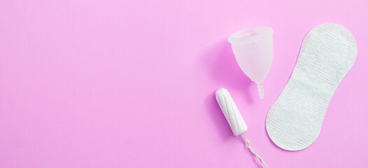 Menstrual hygiene products including tampon, menstrual cup and sanitary pad on lilac background with copy space