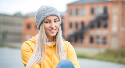 Smiling young beautiful woman looking at camera. Copy space. Outdoors daylight. Half length of pretty girl with positive emotion, smiley expression. Female person wearing casual clothing