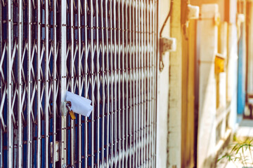 White paper notification attached to closed retractable folding metallic gate.Metal collapsible sliding grille door normally use at shop houses in Asia. Bulletin sticking out at the gate of the house.