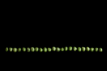Green peas on the black background | line of peas