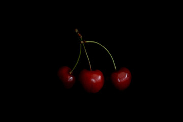 Red cherry berries on a black background | three cherries