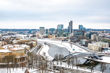 Obraz premium Vilnius, capital of Lithuania, beautiful scenic aerial panorama of modern business financial district architecture buildings with snow, Neris river and bridge in winter