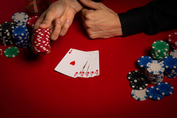 Casino. Poker. Hands of a gambler. Poker player. Game chips and dice lie on the table against a red background. Game chips for betting in gambling. Dice. Poker chips. 