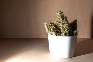 Medical marihuana buds inside a coffee cup. Selective focus on brown background.