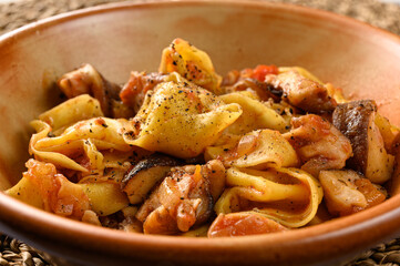Cheese tortellini with mushrooms in plate on natural matting