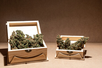 Ready-to-use medical marihuana buds inside two wooden boxes. Selective focus on brown background.