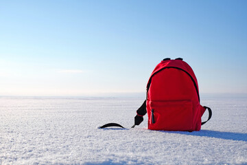 Red packbag on snow and blue winter sky. Copy space.
