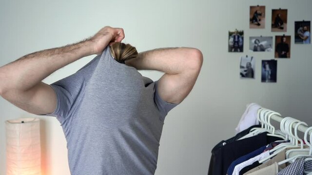 Attractive bearded man is taking t-shirt off
