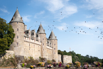 Fortress of Josselin with pigeons flying over it in Brittany, France.