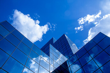 Fototapeta na wymiar the mirrored surface of building, in which clouds, another buildings and blue sky are reflected 