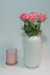 Pink roses in a vase and an extinguished candle