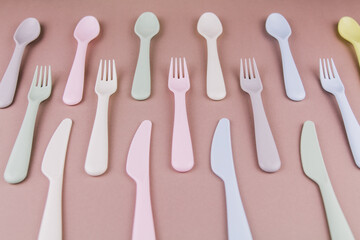 set of plastic cutlery in different colors spoons forks knives on the kitchen table and...