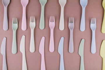 set of plastic cutlery in different colors spoons forks knives on the kitchen table and...