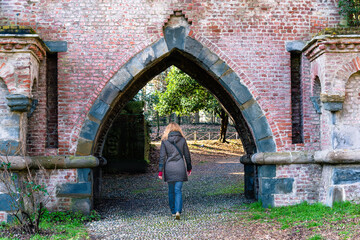 Fototapeta na wymiar Woman from behind entering in a gate in the famous gardens of Monza park (Italy)