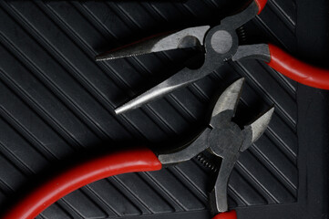 Fototapeta premium The flat nose pliers and pasatige are on the tool box. close-up.