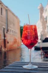 Glass of refreshing Aperol Spritz cocktail served on the deck bar in Venice. Traditional venetian...