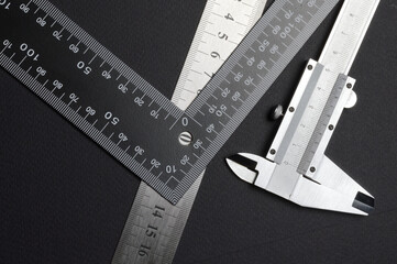 measuring tool, ruler square and caliper. lie on a dark background. close-up.