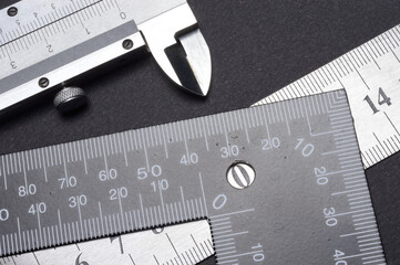 measuring tool, ruler square and caliper. lie on a dark background. close-up.