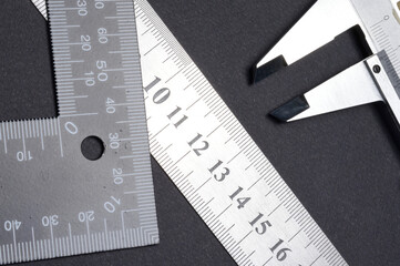 measuring tool, ruler square and caliper. lie on a dark background. close-up.