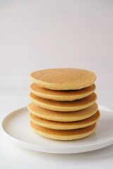 Freshly cooked soft delicious gluten free pancakes stacked on white plate, close up. Space for text. Healthy sweet food.