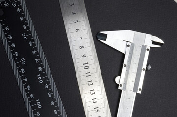 measuring tool, ruler square and caliper. lie on a dark background. close-up.