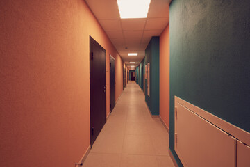 ypical ordinary corridor of a residential building, painted in bright colors, metal unnamed apartment doors, rich shades