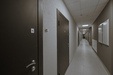 ypical ordinary corridor of a residential building, painted in bright colors, metal unnamed apartment doors, rich shades