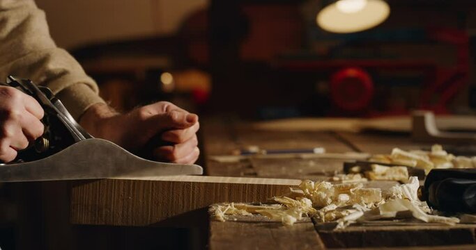 Cinematic shot of master artisan luthier working on creation of handmade fine quality wood violin in creative workshop. Concept of spiritual instrument, handmade, art, orchestra, artisan, music.