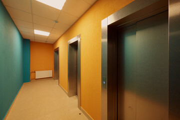 Obraz premium ypical ordinary corridor of a residential building, painted in bright colors, metal unnamed apartment doors, rich shades