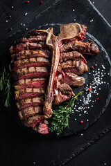 Steak on the bone. Grilled beef steak with rosemary, salt and pepper. Top view. vertical image,...