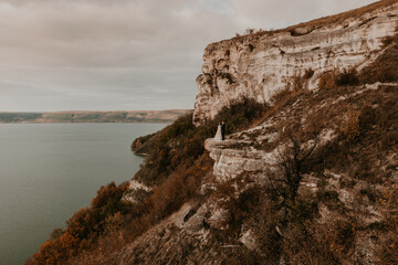 groom in suit and the bride in a dress stand on a stone cliff Aerial view from drone